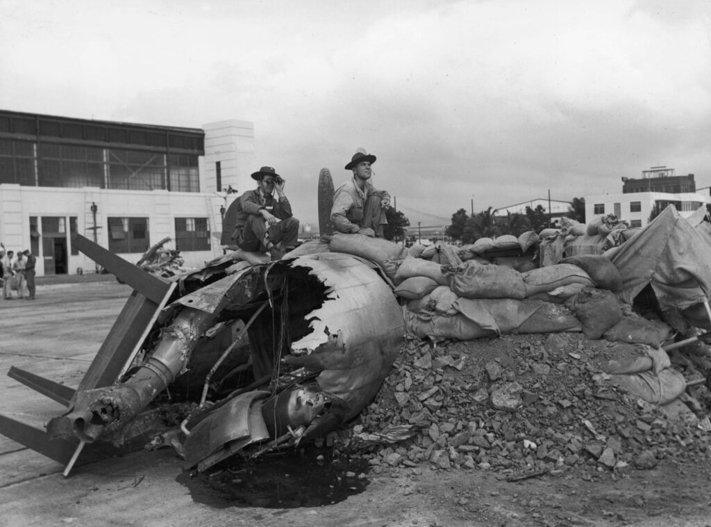 two US troops sitting on a bomber wreckage after Pearl Harbor attack