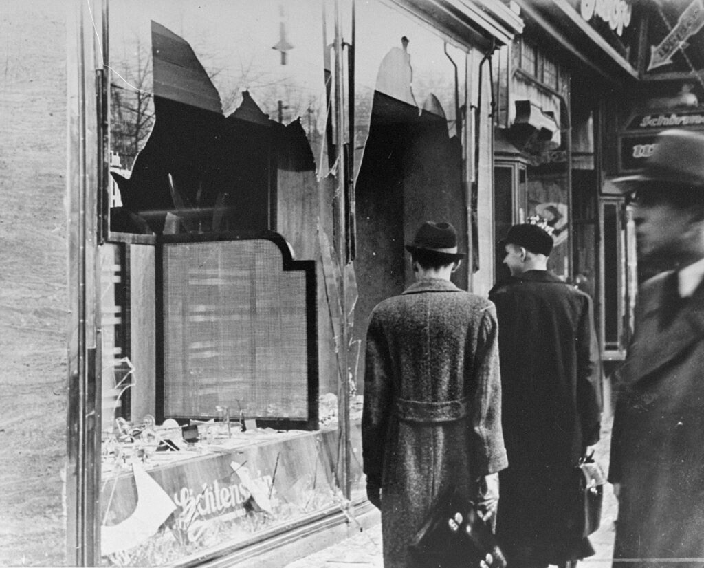 germans pass by a jewish-owned business destroyed on Kristallnacht